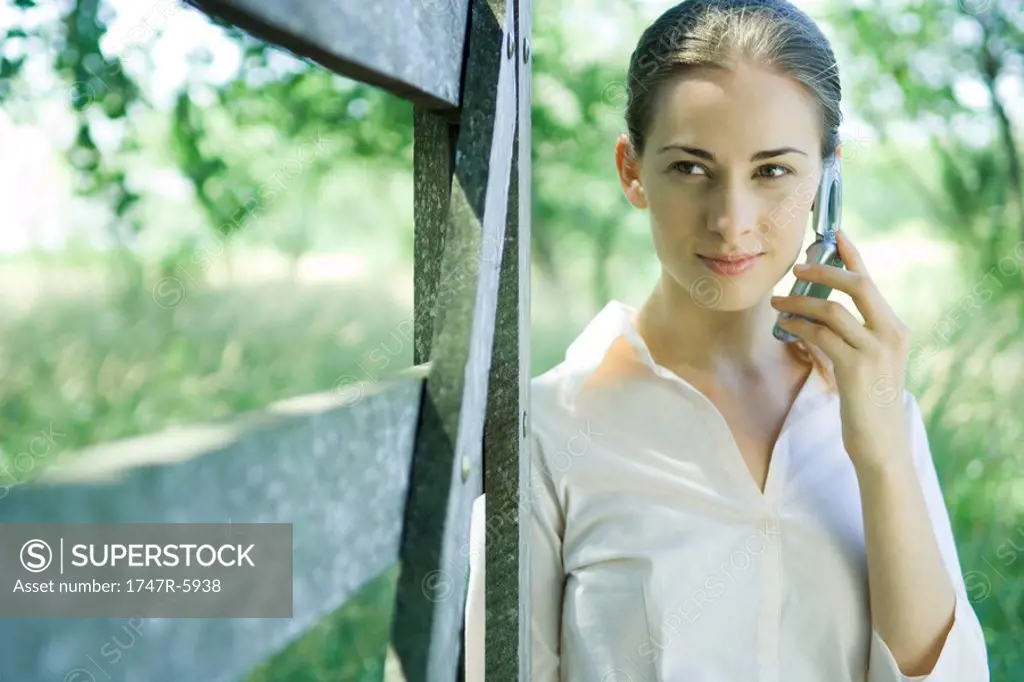 Businesswoman using cell phone outdoors, near gate