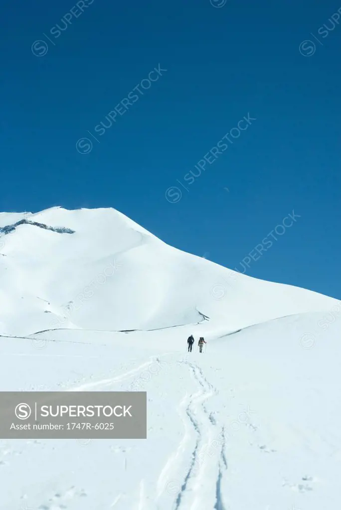 Skiers moving uphill in distance