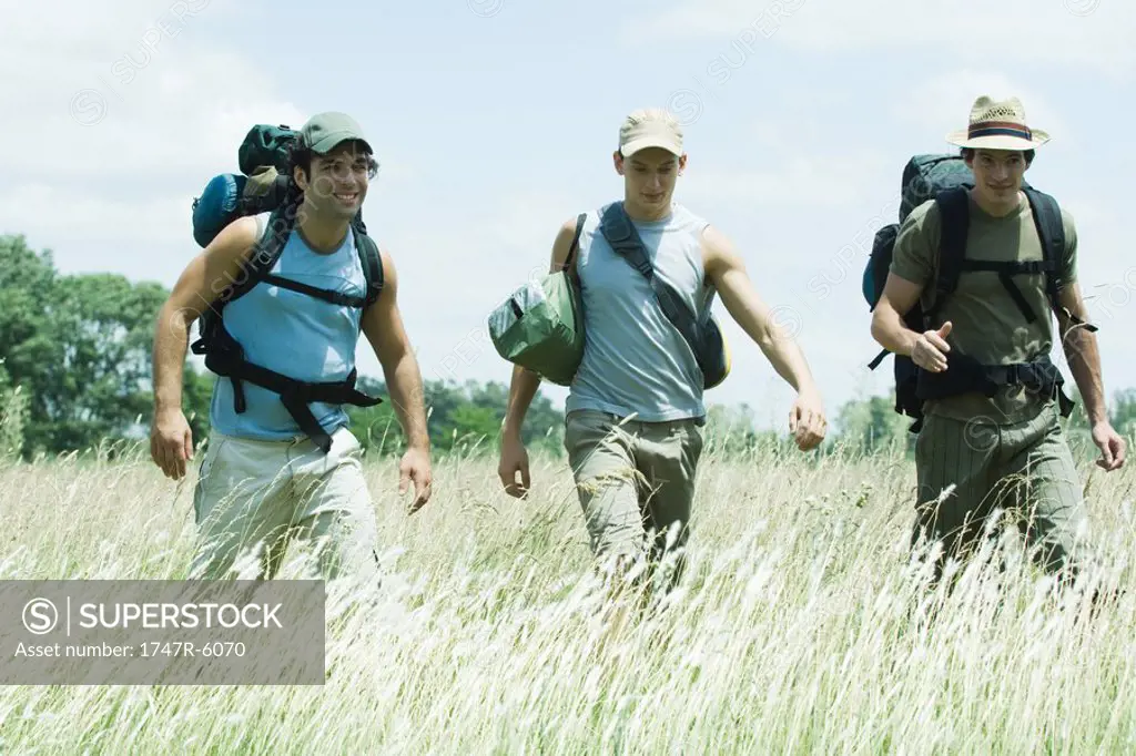Three hikers walking through field