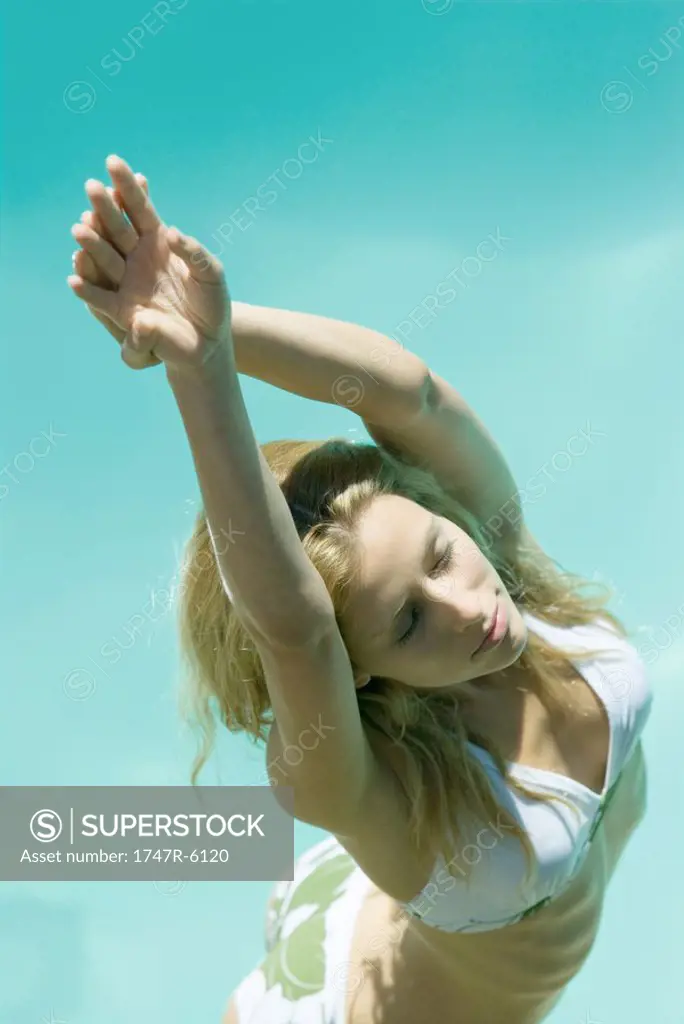 Young woman standing in bikini with hands over head