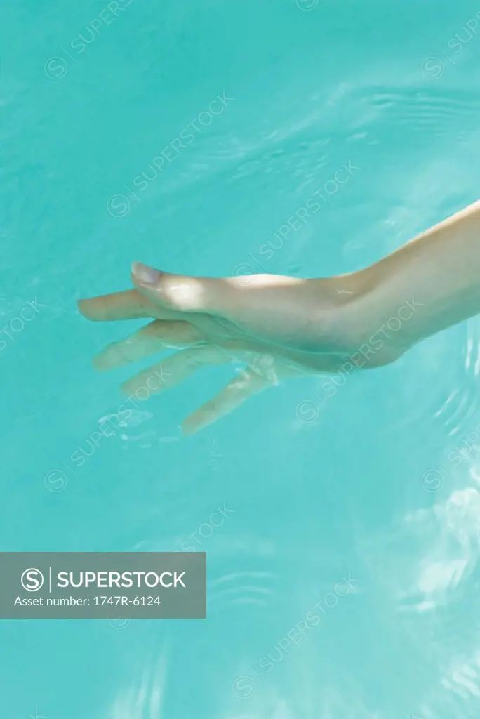 Young woman dipping hand into water, close-up
