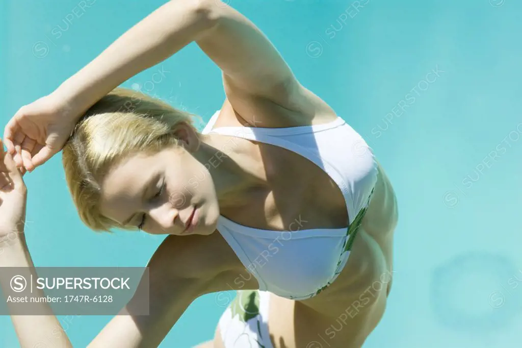 Young woman wearing bikini, stretching arms over head