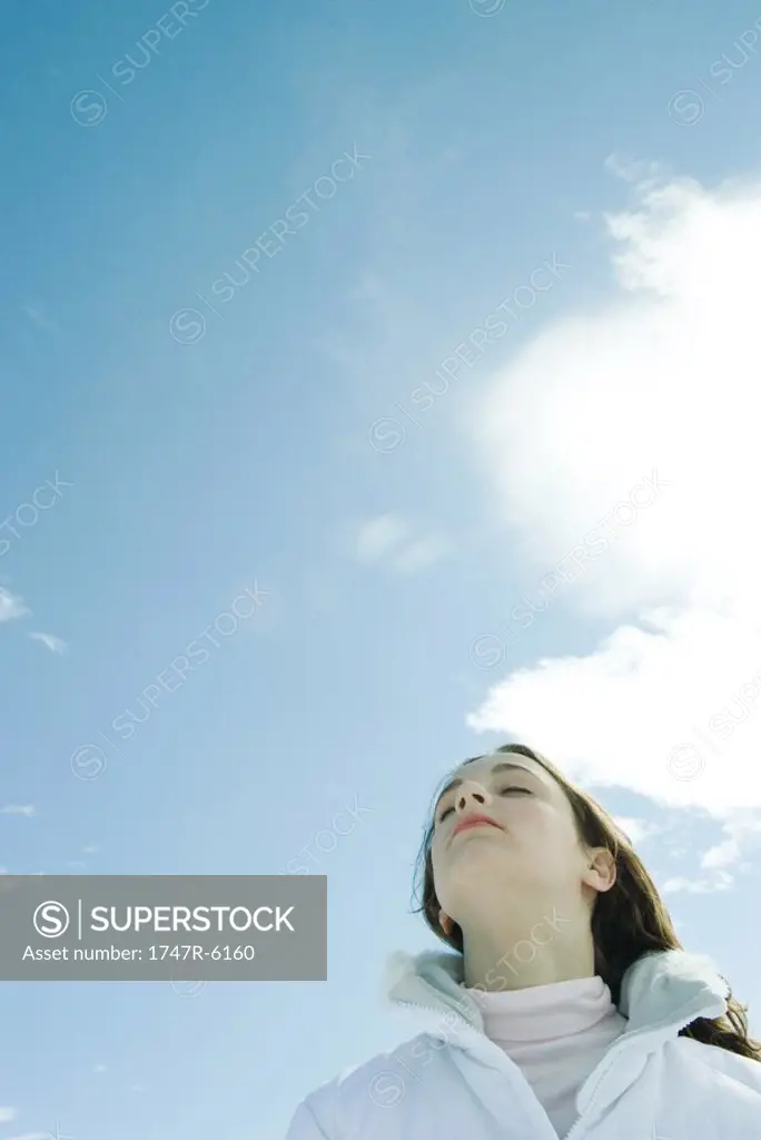 Teen girl with eyes closed, low angle view