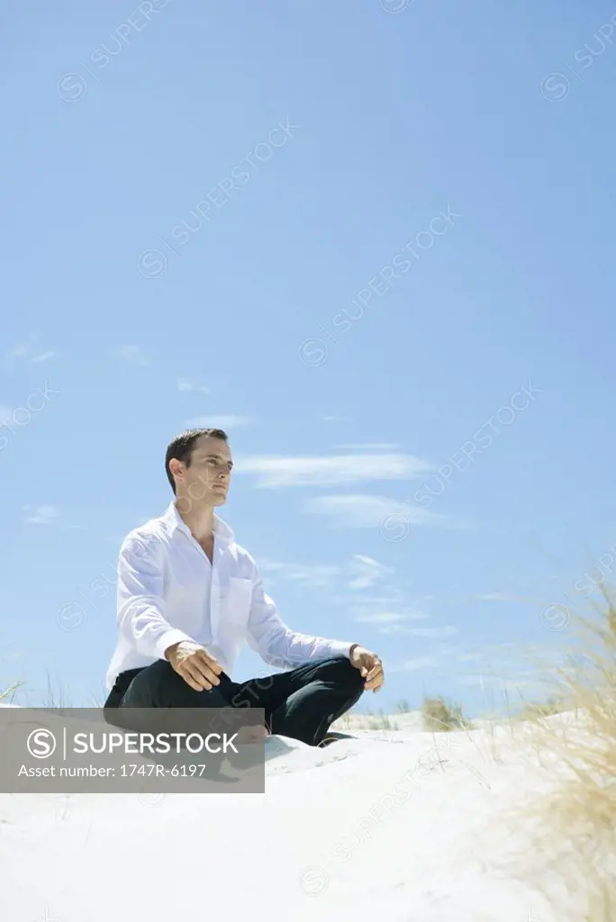Man sitting indian style on dune