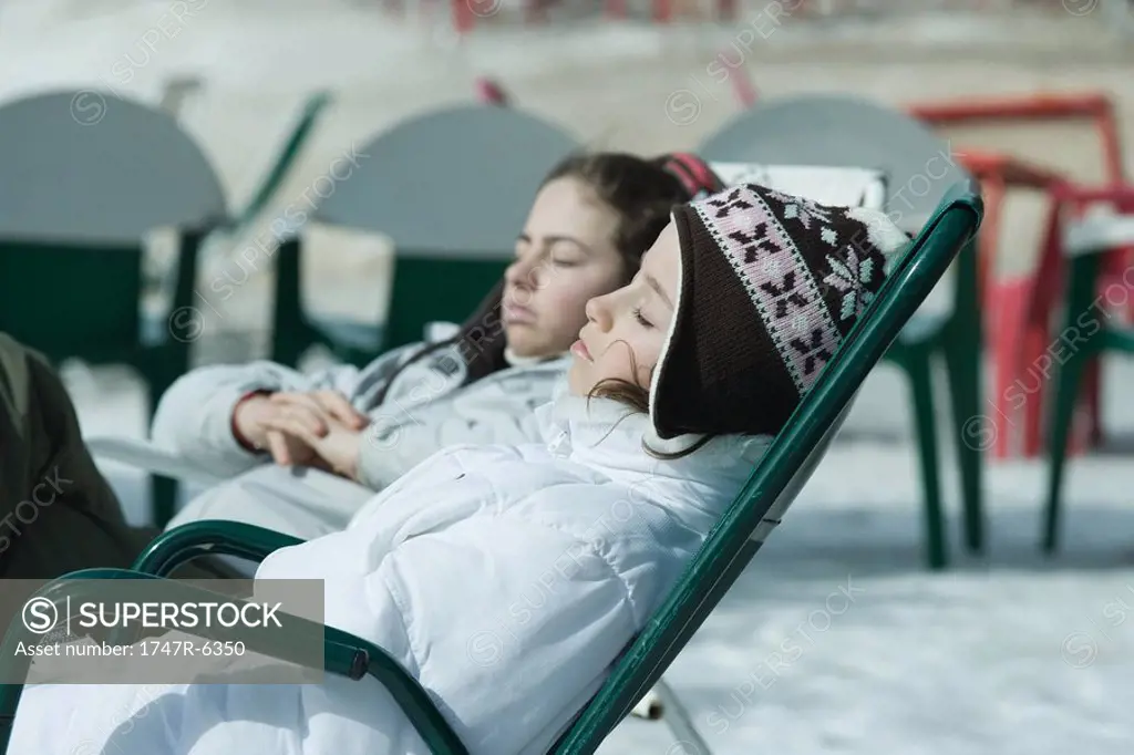 Teen girl sitting in chairs at ski resort, relaxing in sun