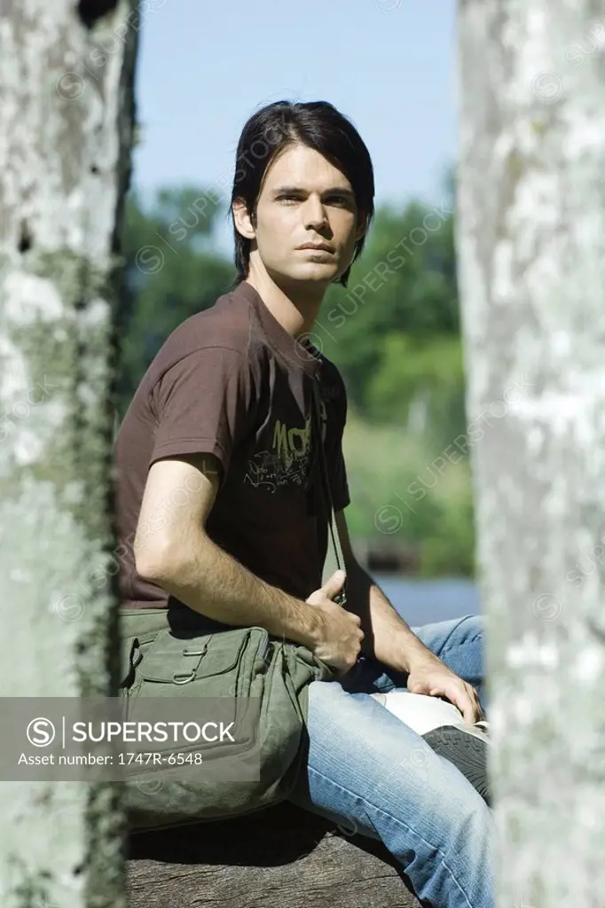 Man sitting outdoors wearing messenger bag