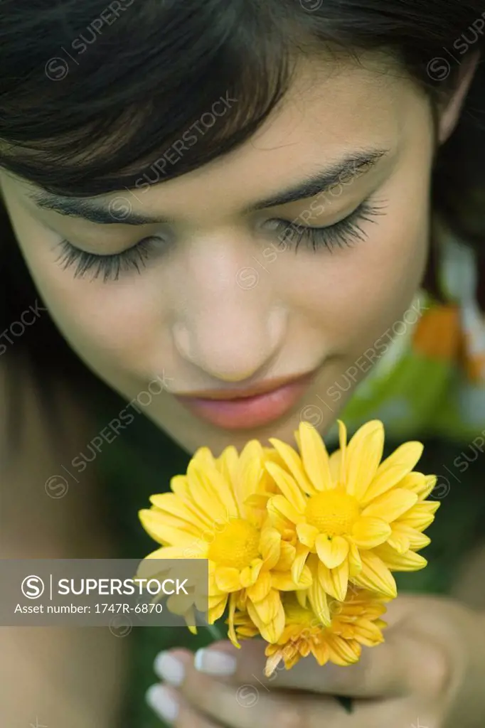 Young woman smelling flowers, eyes closed, high angle view, cropped
