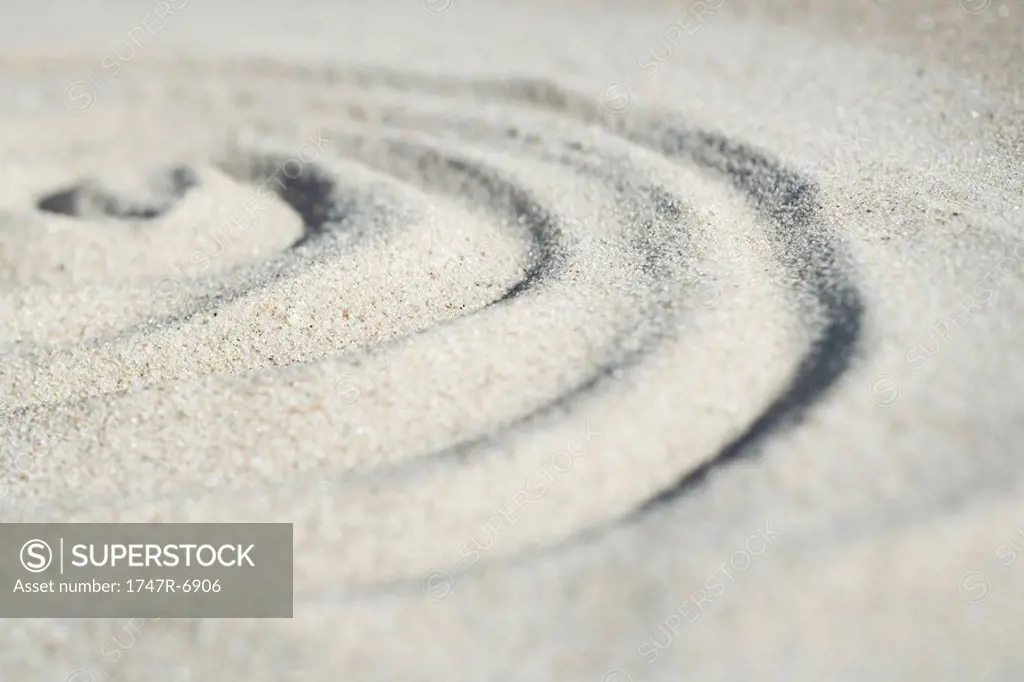 Spiral shape drawn in sand, close-up, surface level