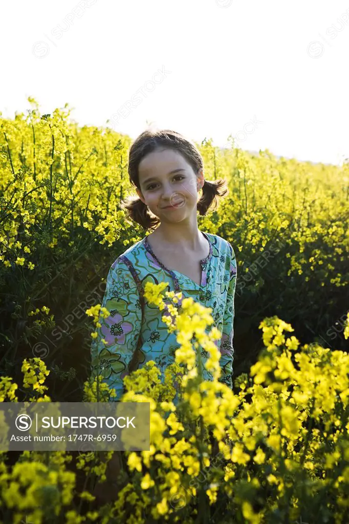 Girl standing in field of canola in bloom