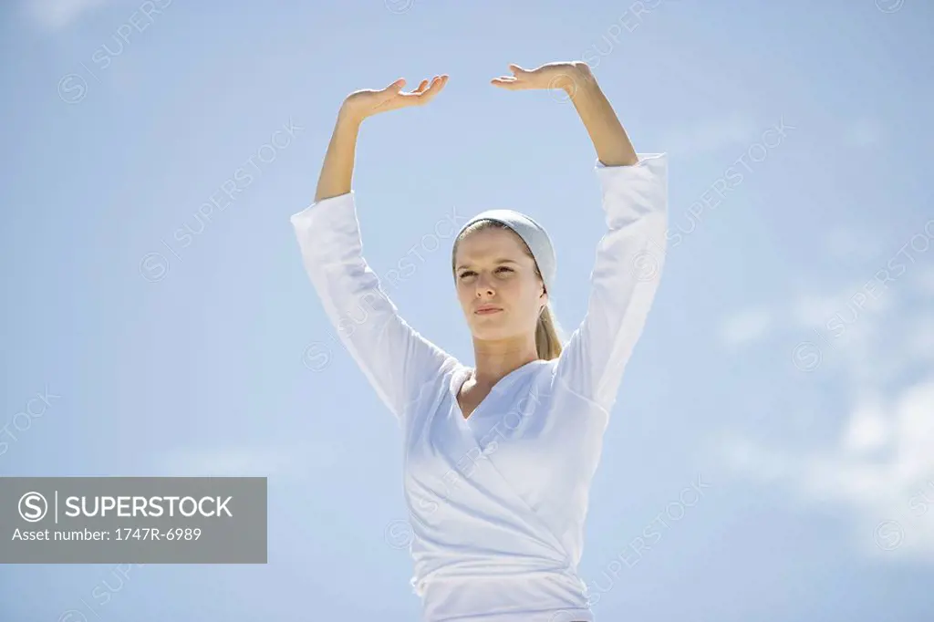 Young woman with arms over head, low angle view