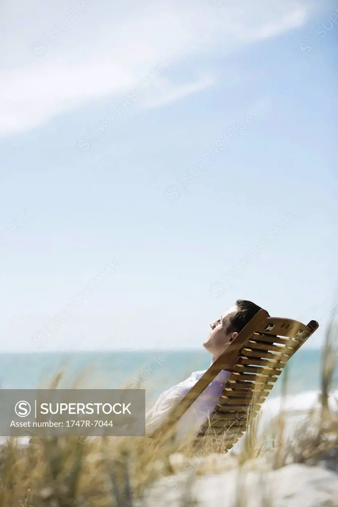 Young man sitting in deck chair