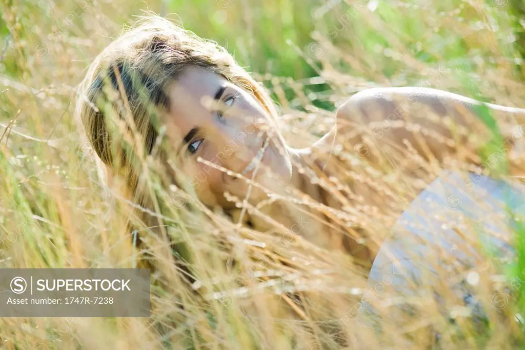 Young woman reclining in tall grass, smiling