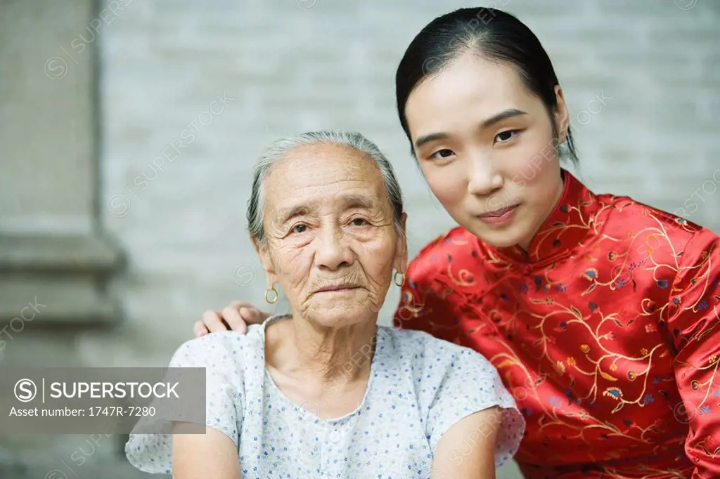 Young woman wearing traditional Chinese clothing posing next to elderly woman, portrait