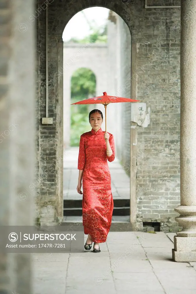 Young woman wearing traditional Chinese clothing, walking with parasol