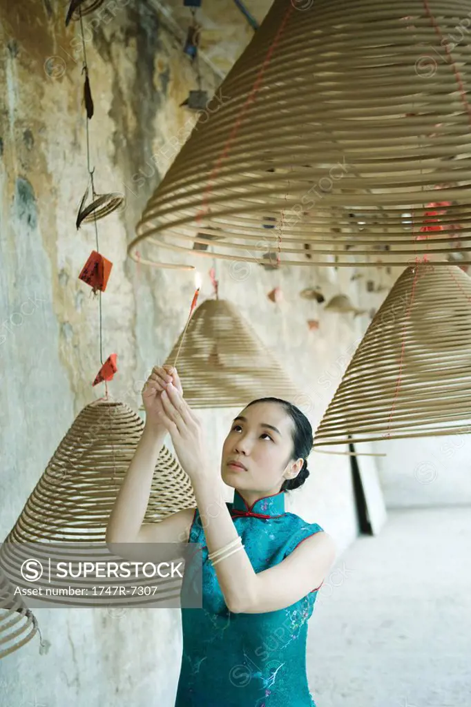 Young woman wearing traditional Chinese clothing, lighting spiral of incense