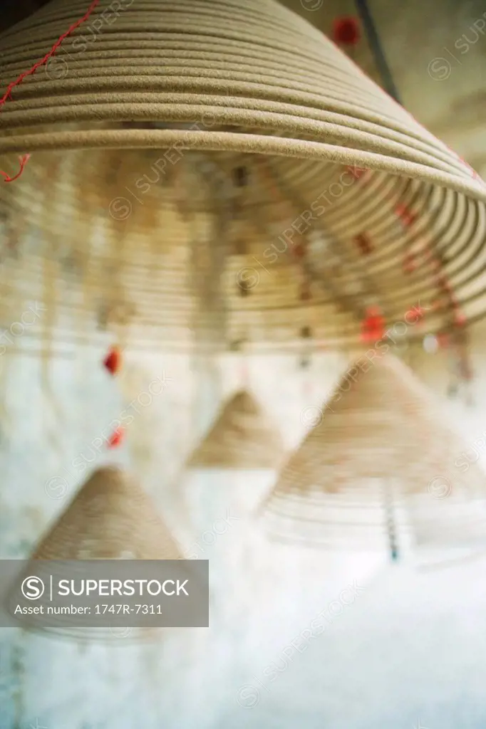 Spirals of incense hanging from ceiling, focus on foreground