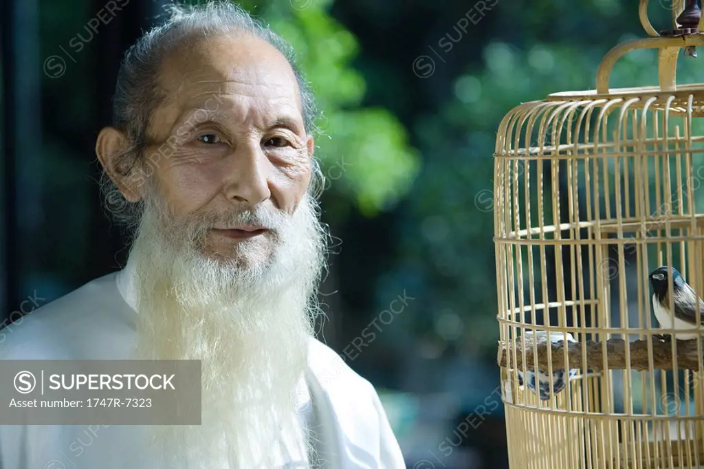 Elderly man wearing traditional Chinese clothing, with bird cage, portrait