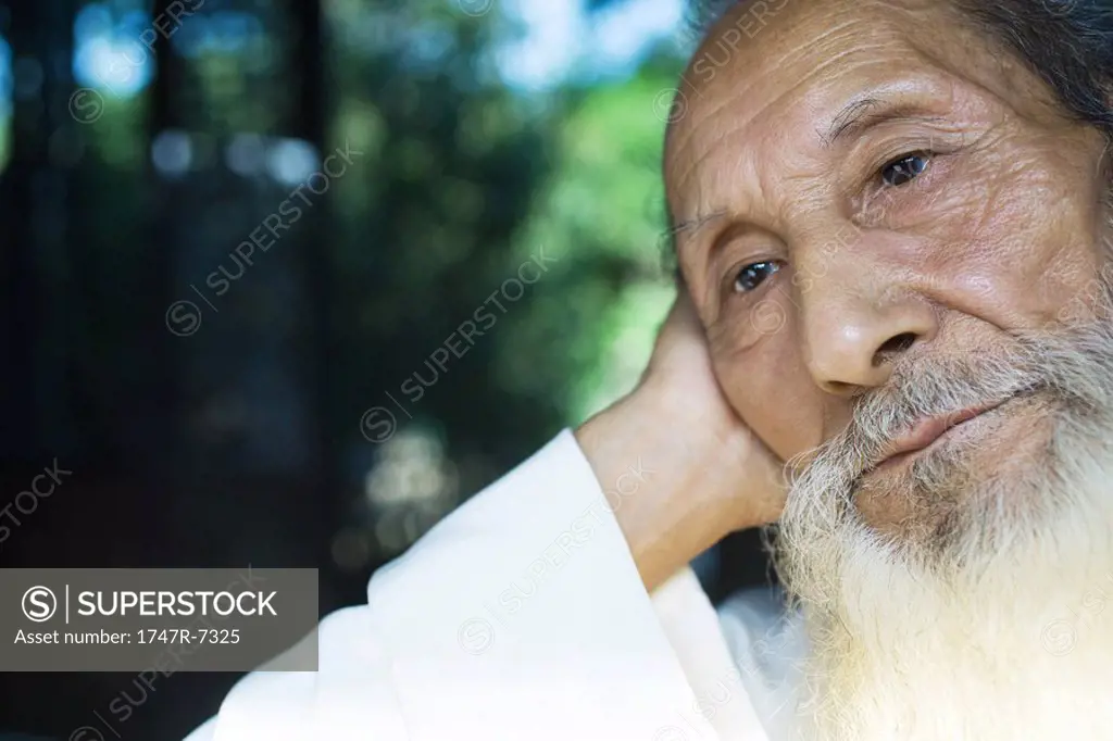 Elderly man leaning head against hand, looking away, close-up