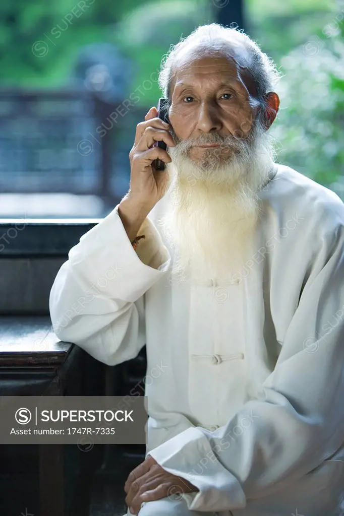 Elderly man wearing traditional Chinese clothing, using cell phone