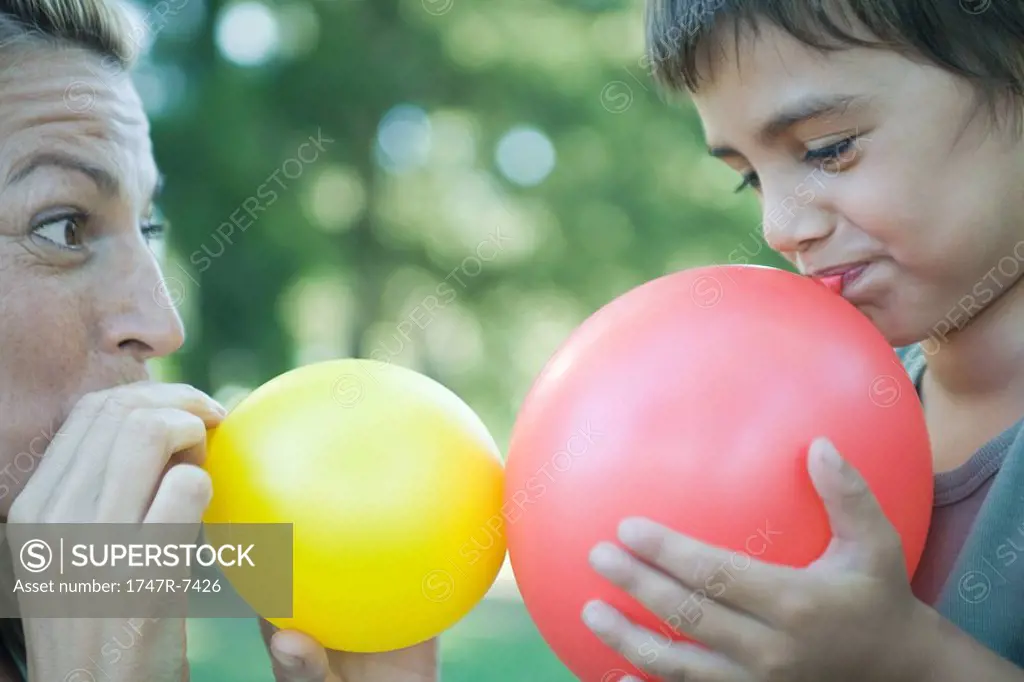 Boy and mother blowing up balloons
