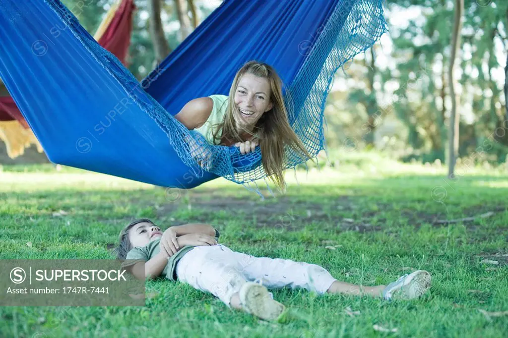 Mother and boy, woman lying in hammock while boy lies on grass