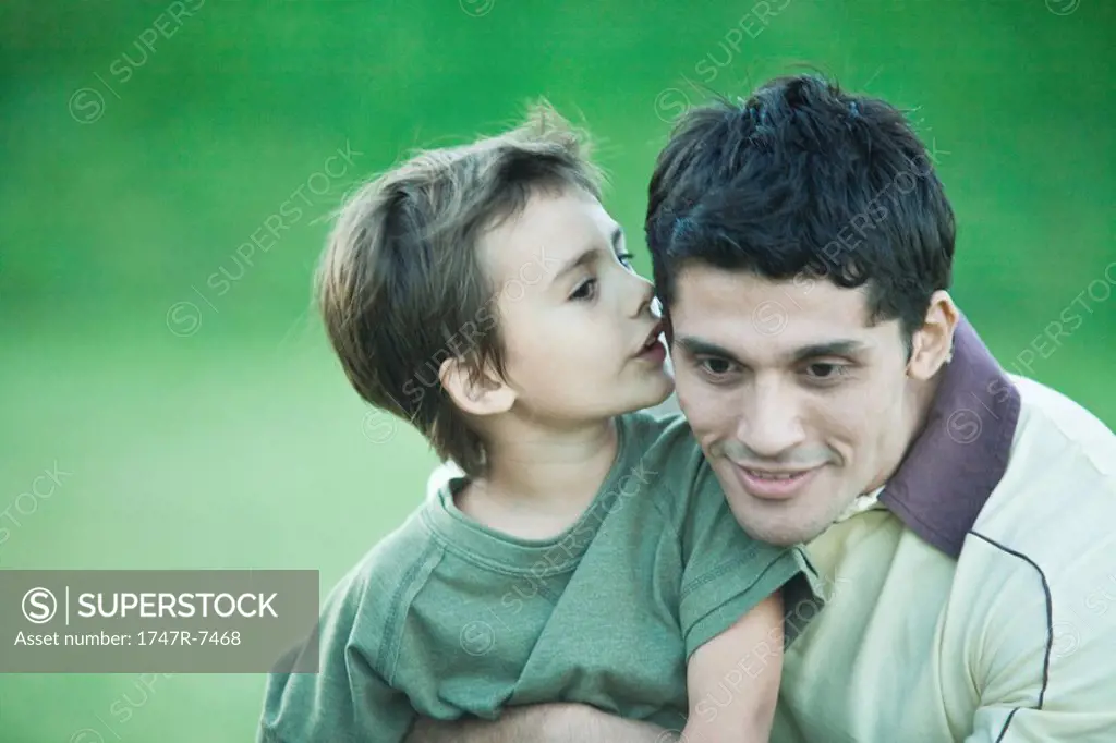 Boy with father, whispering into his ear