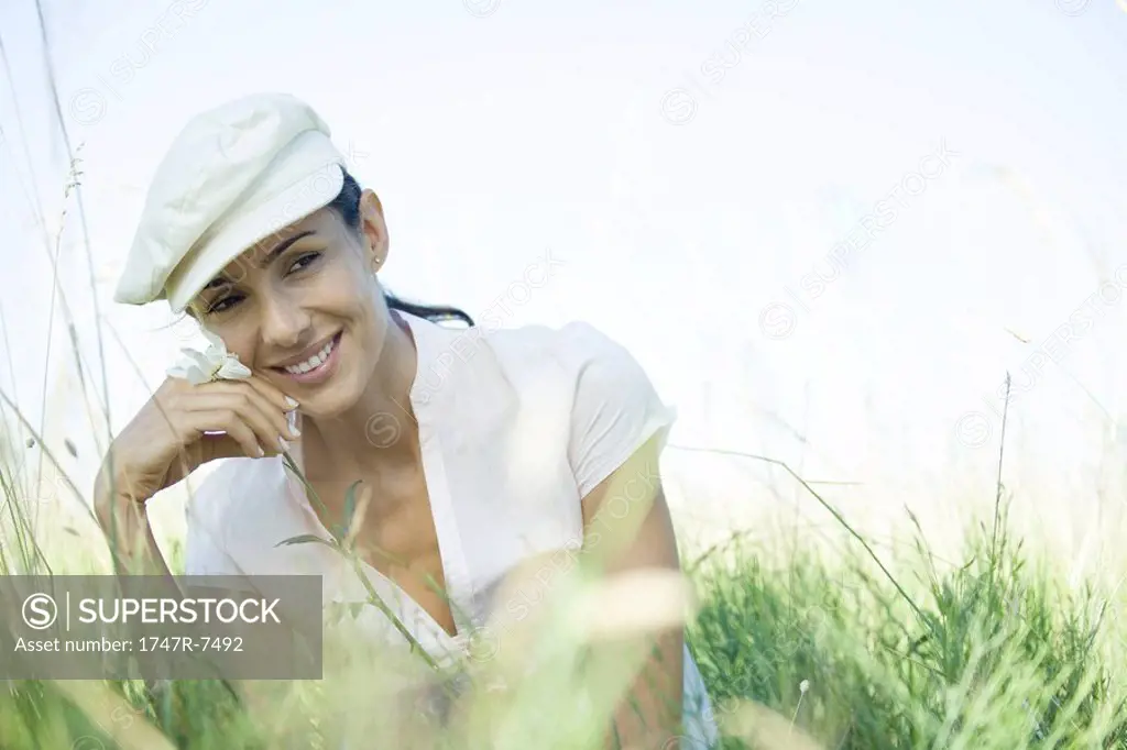 Woman in field holding up flower