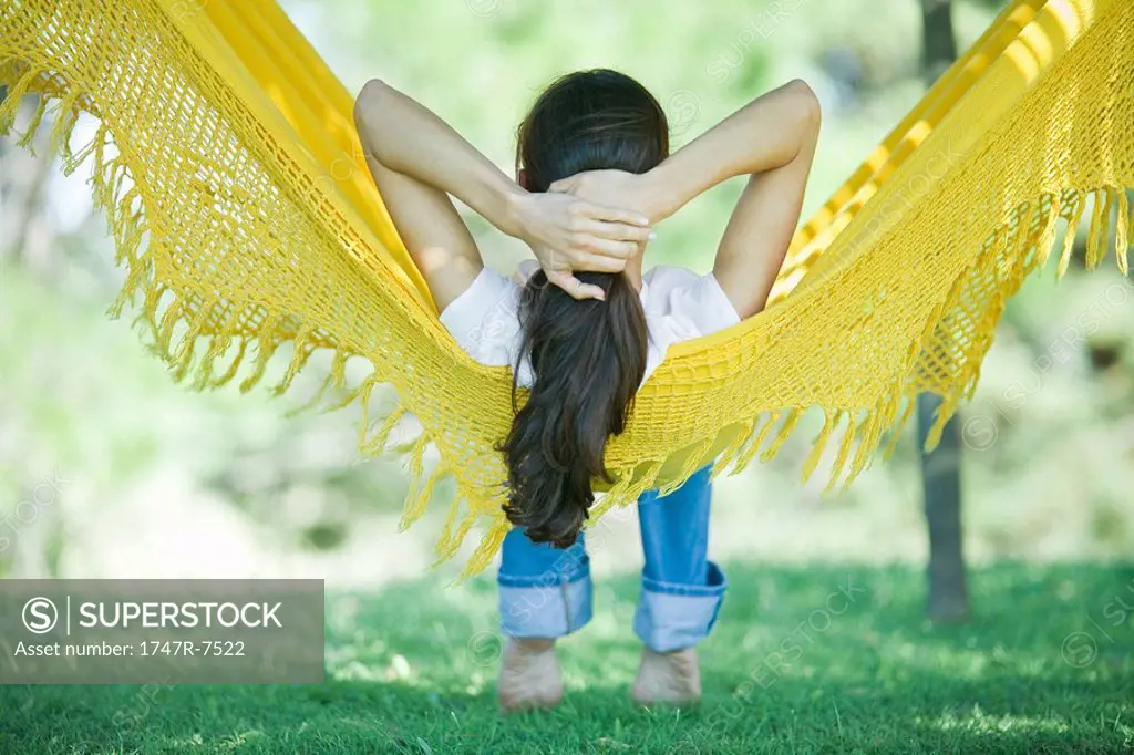 Woman resting in hammock sideways, rear view