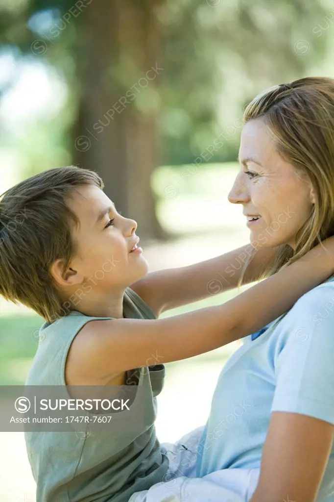 Mother holding son in arms, both smiling at each other, side view