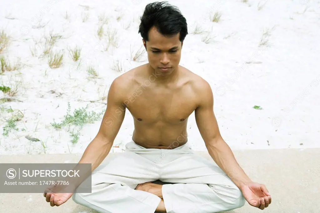 Barechested man sitting in lotus position, high angle view