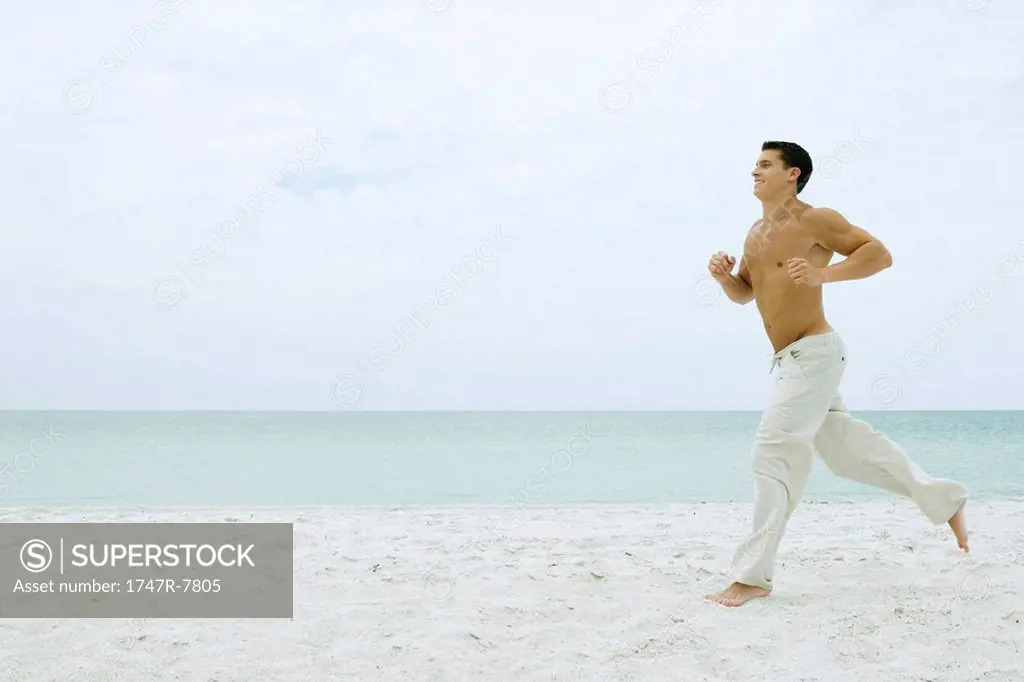 Man running on beach, full length, side view