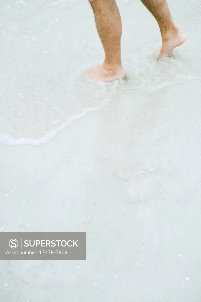 Man standing in surf, knee down