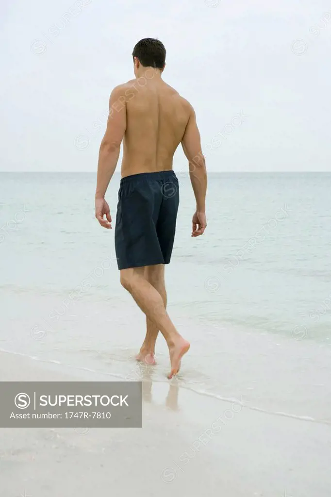 Man walking in surf, rear view
