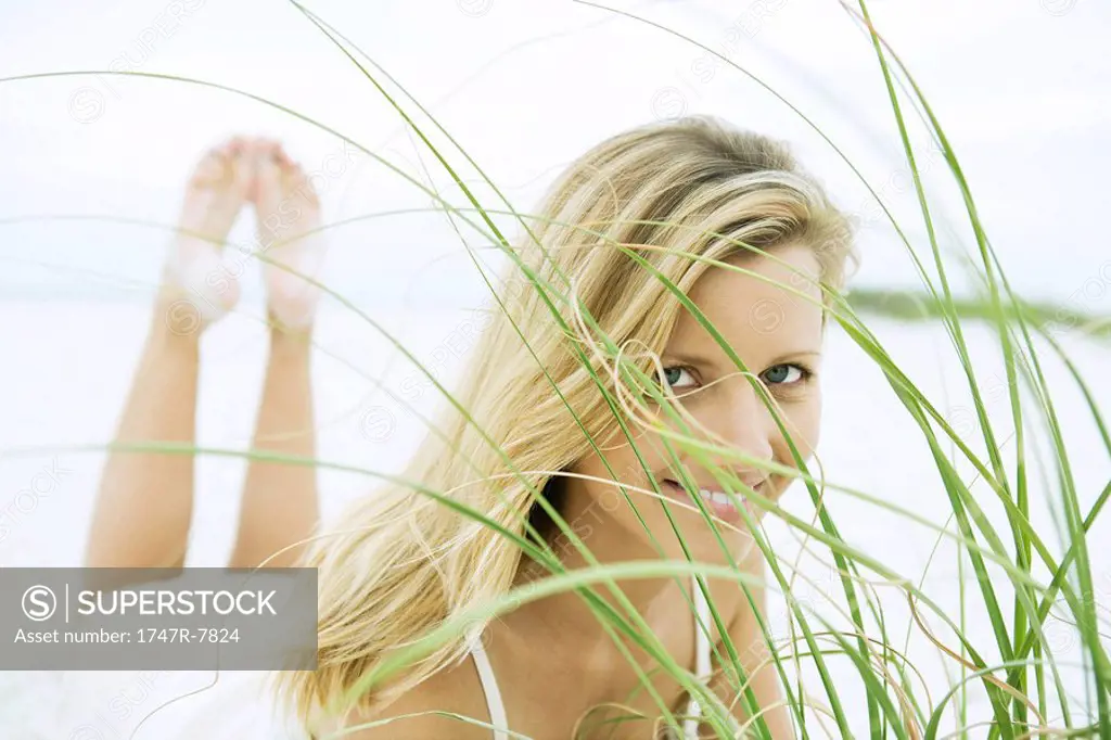 Woman lying on stomach, looking through grass, close-up