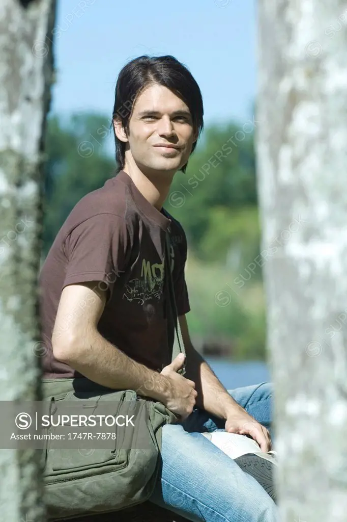 Man sitting outdoors wearing messenger bag