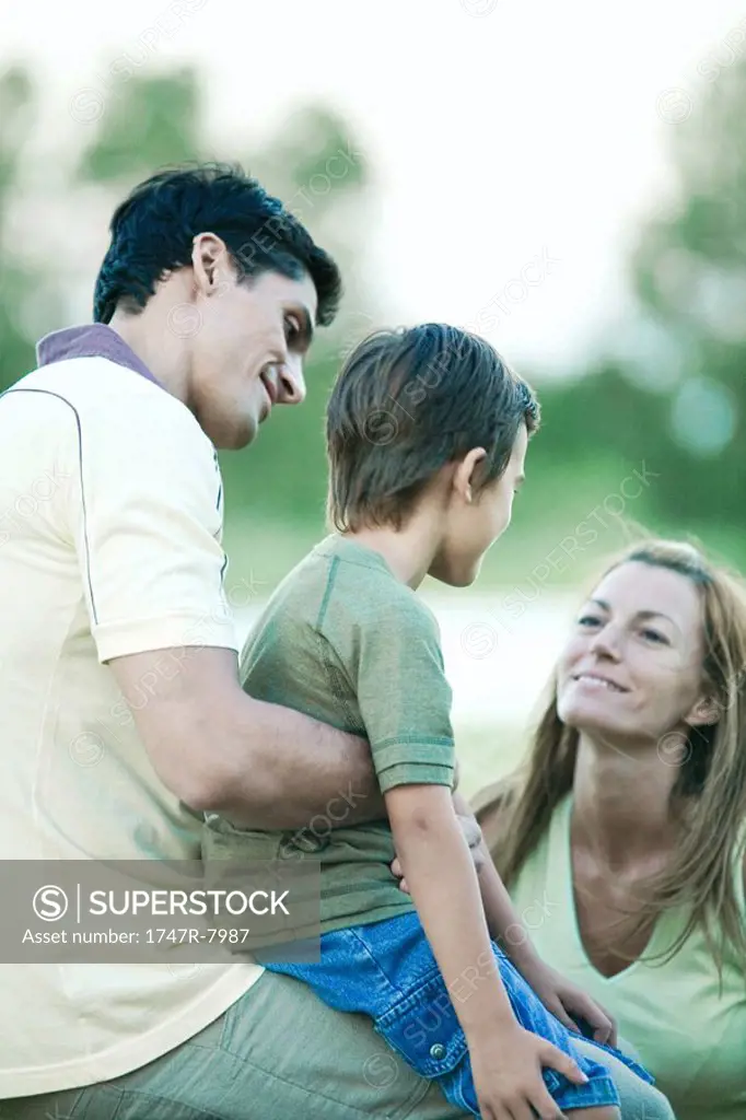 Boy with parents, sitting on father´s lap, looking at mother