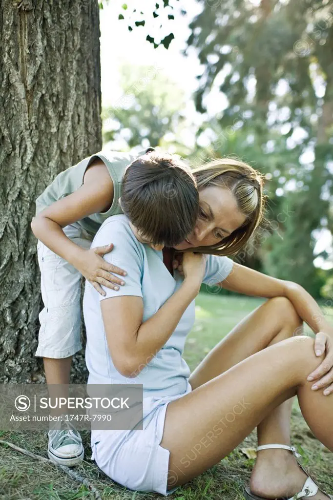 Mother and son outdoors, boy hugging mother from behind