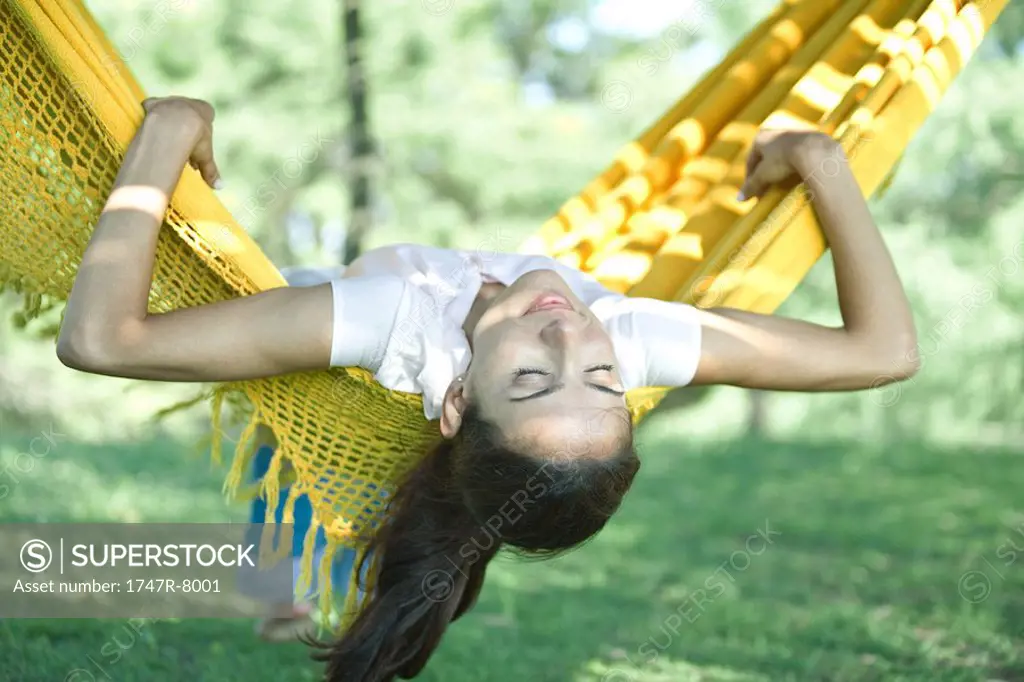 Woman lying in hammock, head hanging upside down