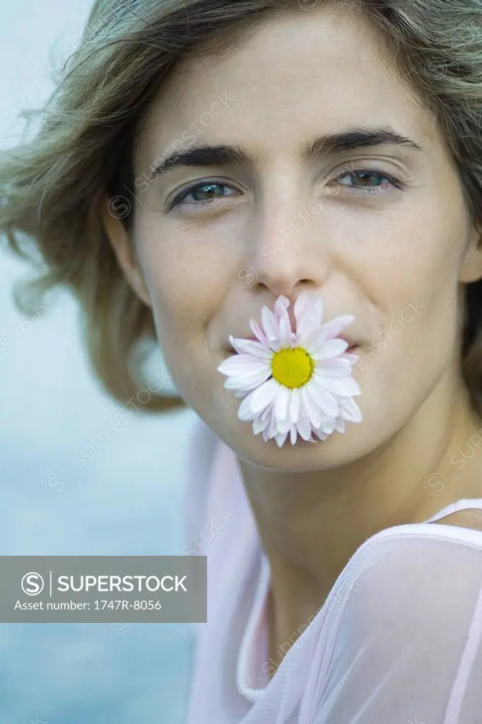 Woman holding flower in mouth, close-up