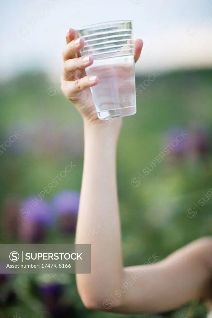 Woman holding up glass of water, cropped