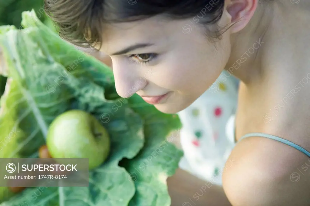 Young woman holding fresh produce, smiling, high angle view