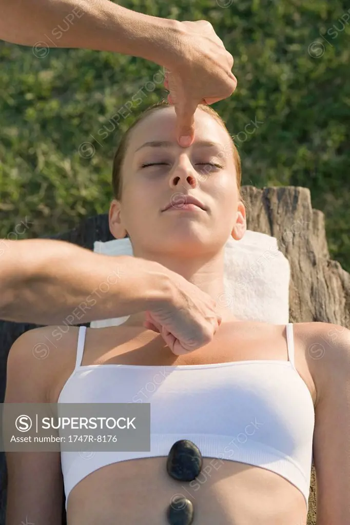 Woman receiving massage with hands and hot stones
