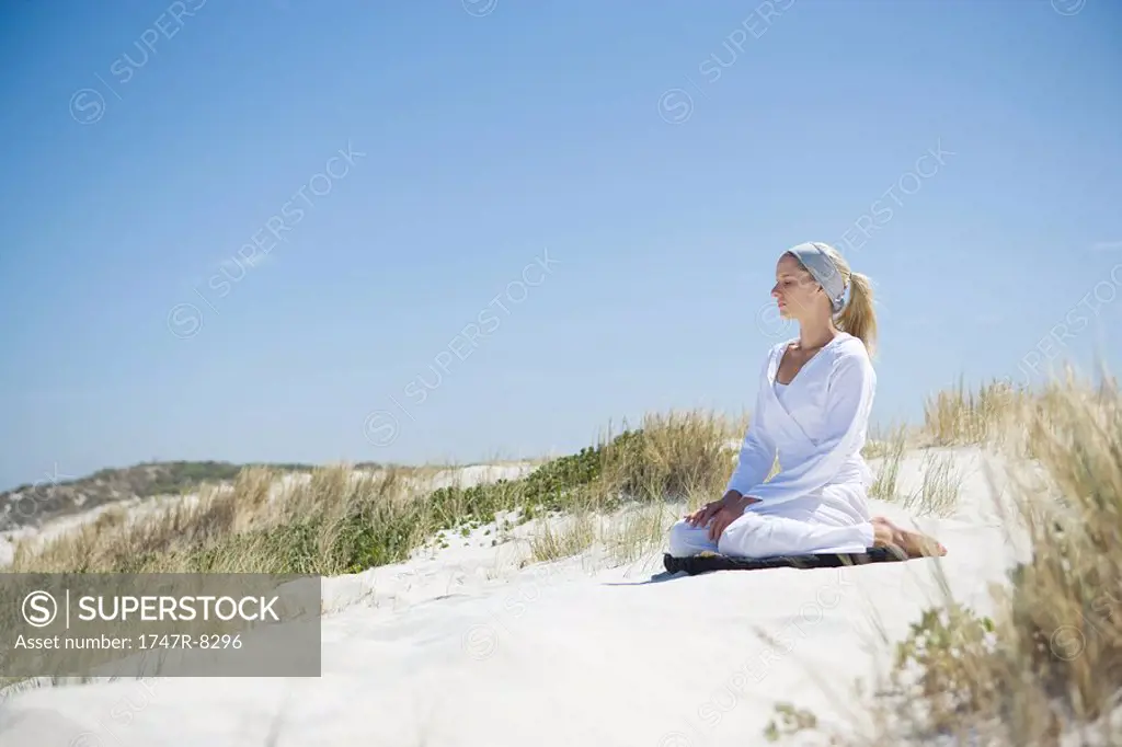 Young woman meditating on beach