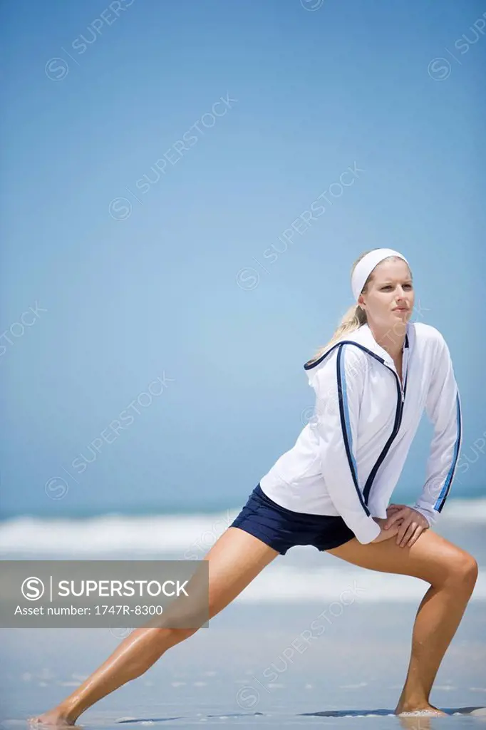 Young woman on beach, stretching