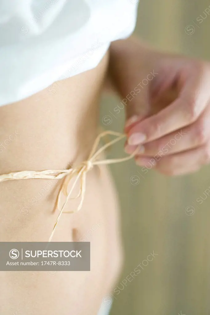 Young woman with piece of raffia tied around waist, cropped