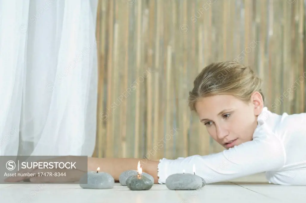 Woman lying on floor, looking at candles