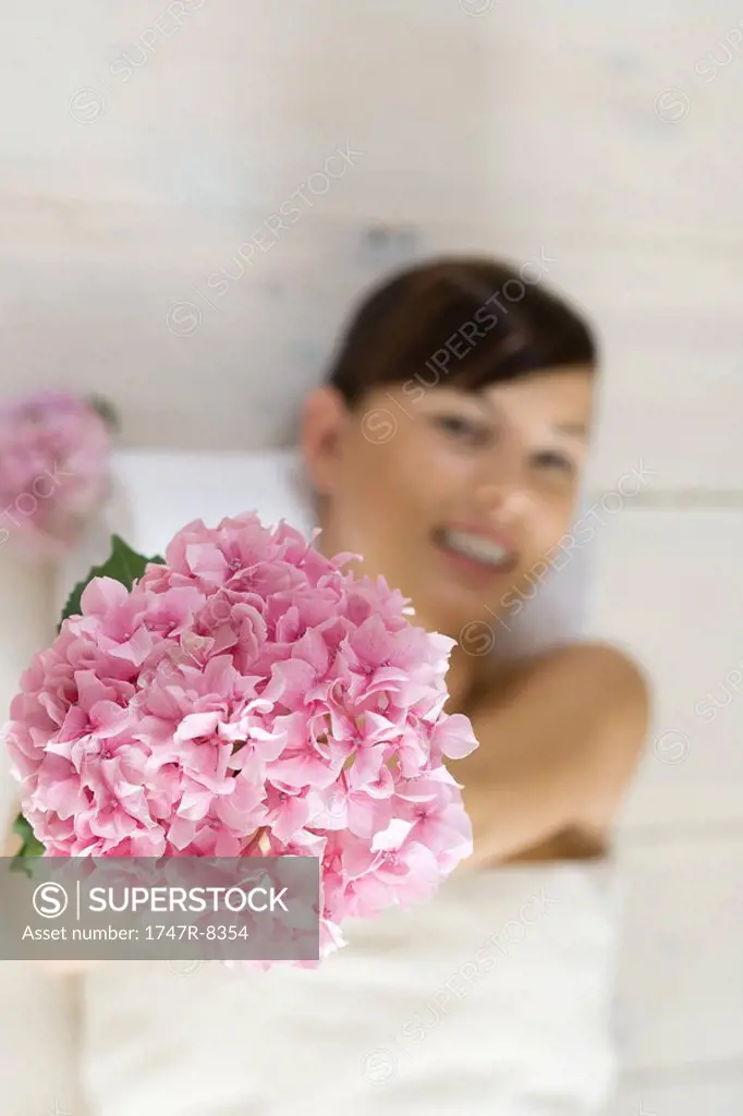 Young woman holding up flower, view from directly above