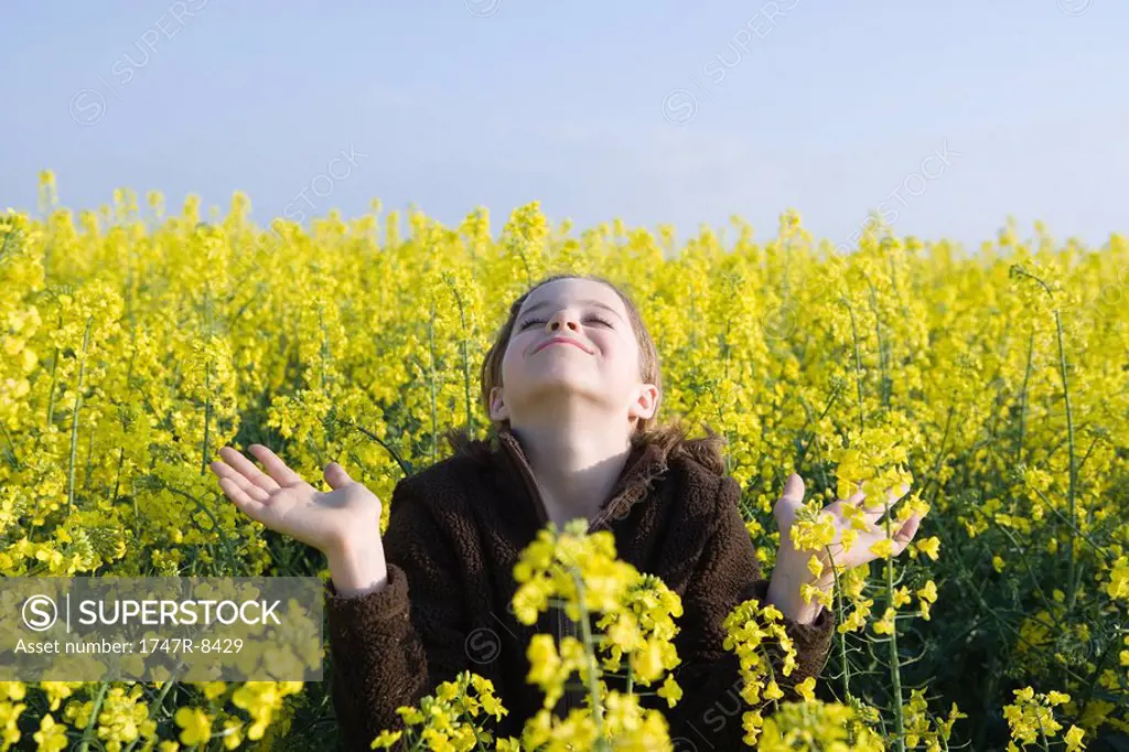 Girl standing in field with hands out, head back and eyes closed