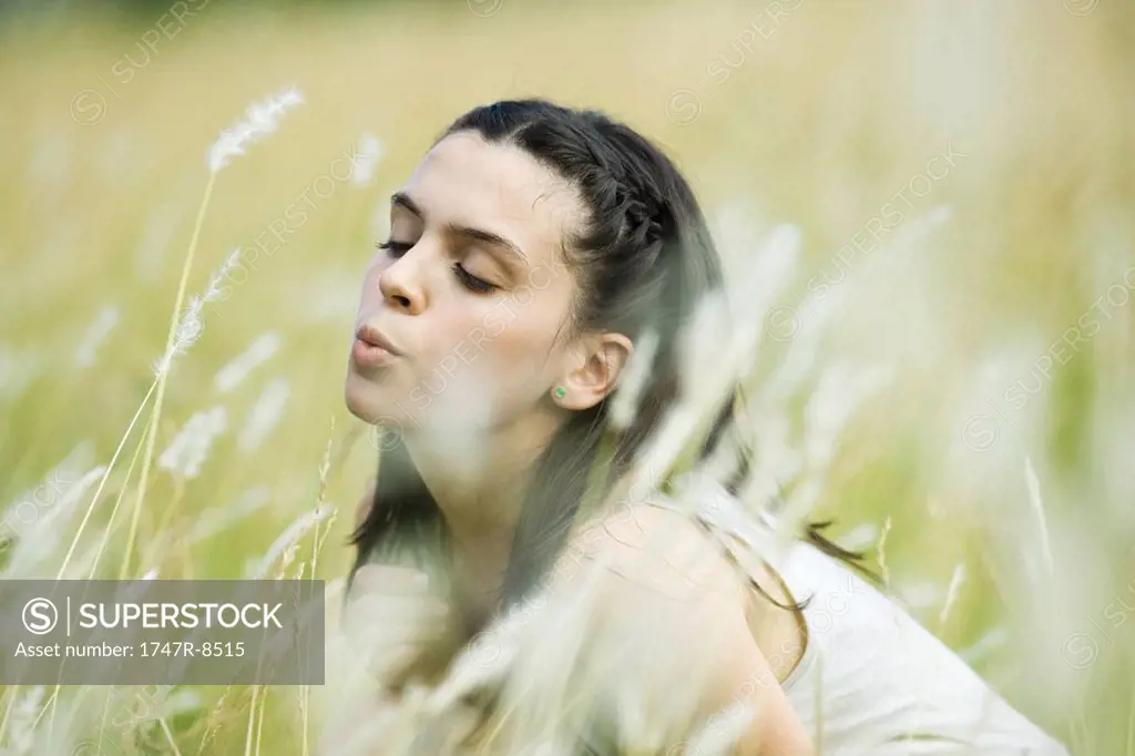 Teen girl in field, blowing tall grass
