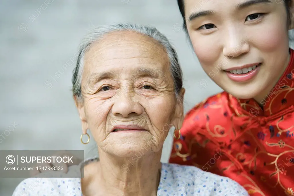 Young woman wearing traditional Chinese clothing posing with elderly grandmother, portrait
